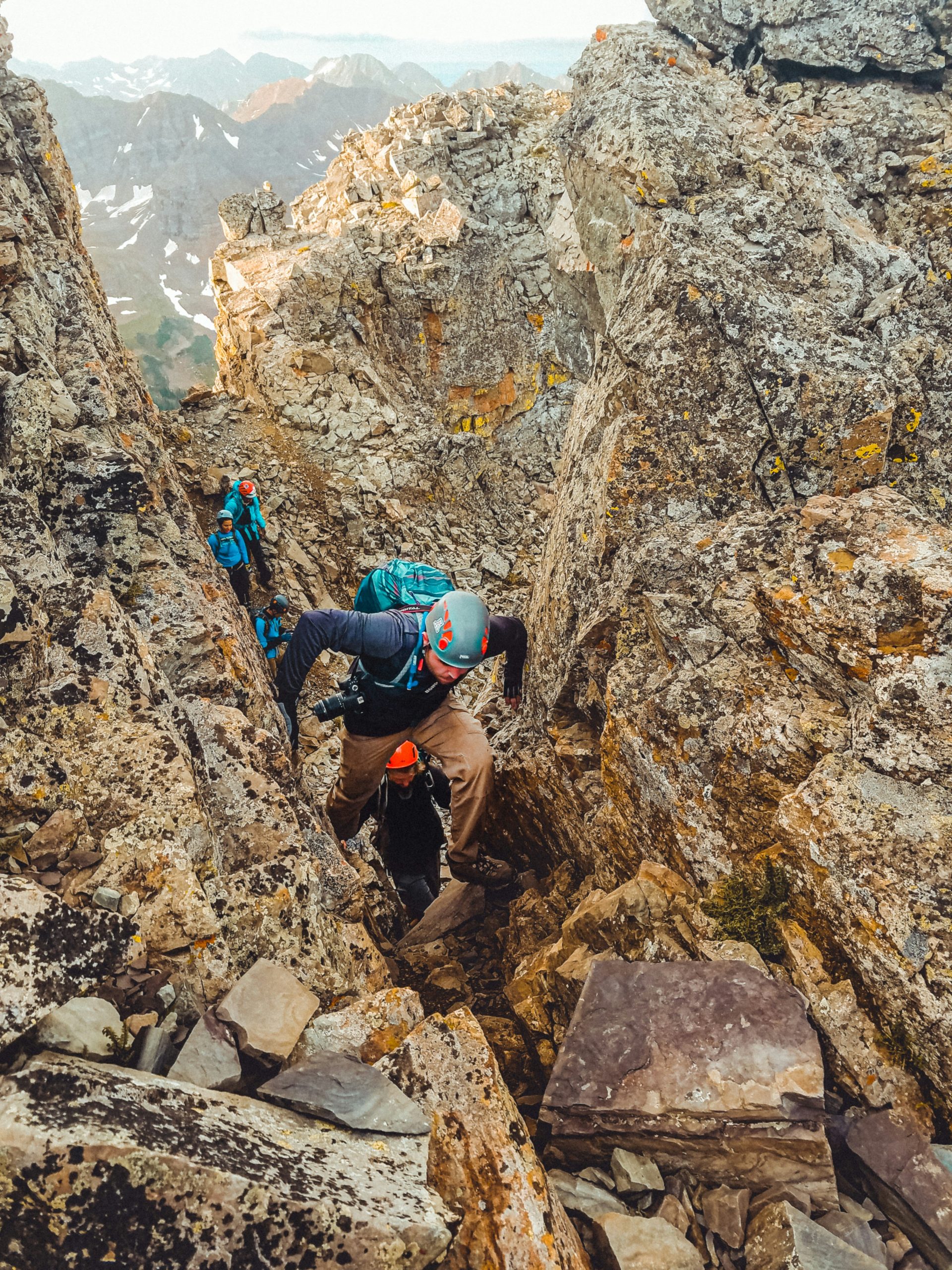 amy-sibert-5Do6T_r-Ujg-unsplash Climber scrambling up a rocky mountain ridge with a backpack.